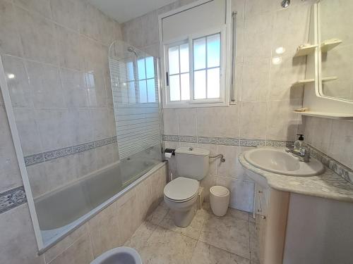 a bathroom with a toilet and a tub and a sink at Torredembarra House in Torredembarra