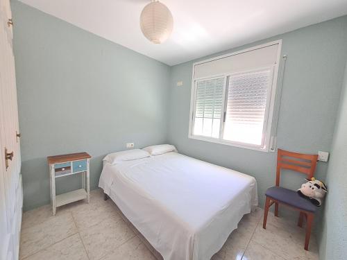 a bedroom with a bed and a chair and a window at Torredembarra House in Torredembarra