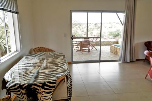 a room with a bed and a table and a patio at Halala Africa Lodge - Eagle Rock Lodge in Malabar