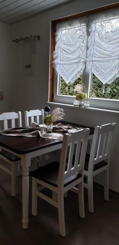 a dining room table with white chairs and a window at ferienhaus-am-scharmützelsee in Wendisch Rietz