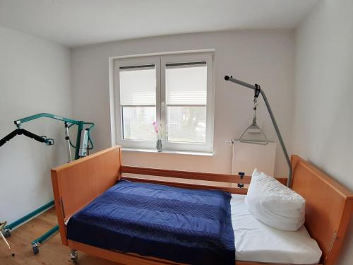 a bedroom with a bed with a blue blanket and a window at Ferienwohnung Schwalbennest in Juliusruh