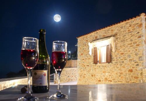 two glasses of wine on a table with a bottle of wine at Stone house with Amazing View in Kótronas