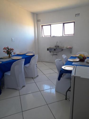 a dining room with two tables and white chairs at Sunset Guesthouse - Mthatha in Mthatha