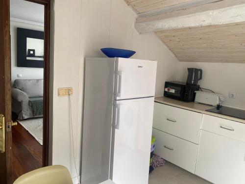 a kitchen with a white refrigerator in a room at piso 2, en Piedrasblancas a 5 min, 1,5 kilometros de la playa de salinas in Piedras Blancas