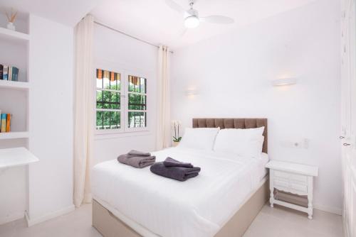 Un dormitorio blanco con una cama blanca y una ventana en El Portet Moraira Apartment Ella, en Moraira