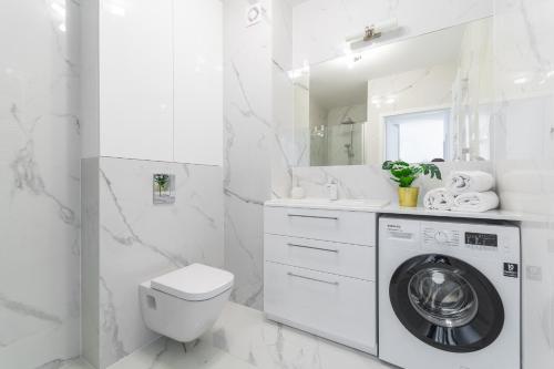 y baño blanco con lavadora. en Apartamenty Mierzeja NCNK Baltic Twins Sztutowo, en Sztutowo