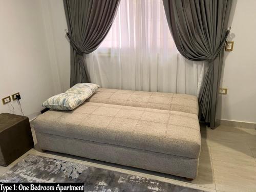 1 dormitorio con 1 cama con cortinas y ventana en Luxury Apartments Beside Mall of Arabia and Dar Al-Fouad hospital - Families only- No Alcoholic Beverages en 6th Of October