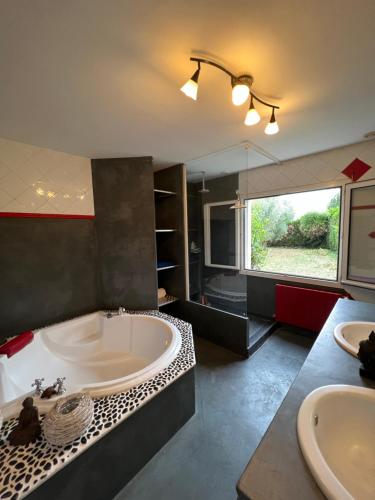 ein großes Bad mit einer Badewanne und einem Waschbecken in der Unterkunft Villa des palmiers in La Jarne