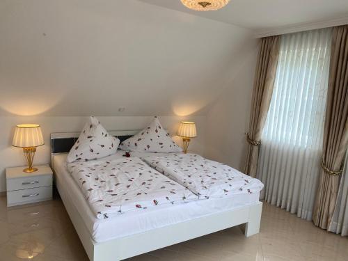 a white bed in a bedroom with two lamps at Ferienhaus Blütentraum in Binz auf Rügen in Binz