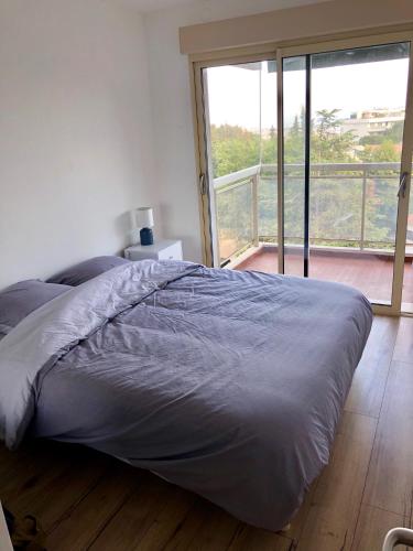 un lit dans une chambre avec une grande fenêtre dans l'établissement Appartement neuf, piscine, terrasse, vue mer., à Cannes