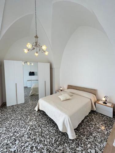 - une chambre blanche avec un lit et un lustre dans l'établissement Stelle secolari, à Corsano