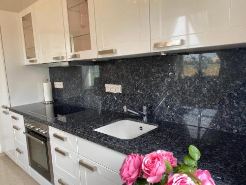 a kitchen counter with a sink and a vase of pink roses at Ferienhaus Blütentraum in Binz auf Rügen in Binz