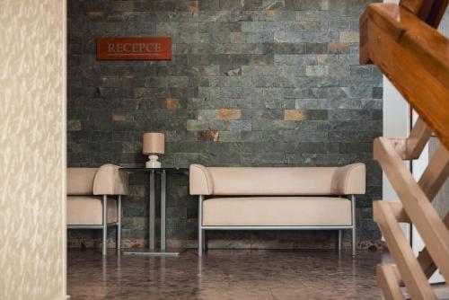 two chairs and a table in front of a brick wall at HOTEL AGRI in Soběšice