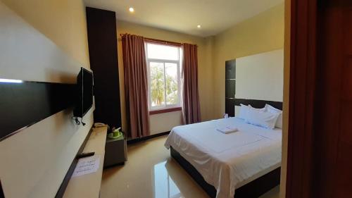 ein Hotelzimmer mit einem Bett und einem TV in der Unterkunft Galaxy Inn in Baubau