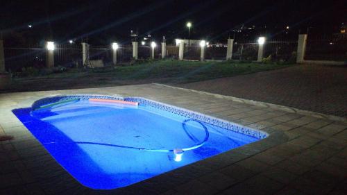 a blue pool with a hose in a yard at night at SUNSET REST BEACH VILLA in Margate