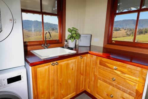 a kitchen with a sink and two windows at Cookes Road Cottage at Conondale in Conondale
