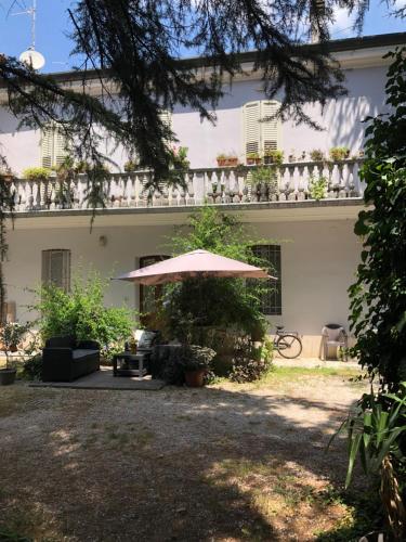 ein weißes Haus mit einem Regenschirm im Hof in der Unterkunft Villa Viola in Forlì