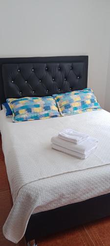 a bed with two white towels on top of it at Dulce hogar baño compartido in Chía