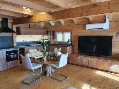 a kitchen with a table with chairs and a large television at La Mazzonette - 4* chalet in de natuur met hottub in Dommartin-lès-Remiremont