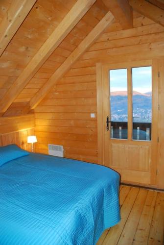 une chambre avec un lit bleu dans une pièce en bois dans l'établissement La Mazzonette - 4* chalet in de natuur met hottub, à Dommartin-lès-Remiremont