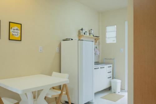 a kitchen with a white refrigerator and a table at Flats Taiba Praia Centro in Taíba