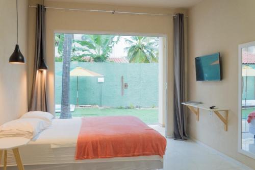 1 dormitorio con 1 cama y puerta corredera de cristal en Flats Taiba Praia Centro, en Taíba