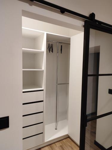 a walk in closet with white walls and shelves at Apartament Narutowicza 56 in Łódź