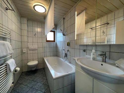 ein Badezimmer mit einem Waschbecken, einer Badewanne und einem WC in der Unterkunft Ferienhaus Sissi in Schwangau