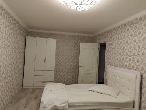 una camera da letto con un letto bianco e un armadio bianco di Квартира в городе Хромтау a Khromtaū
