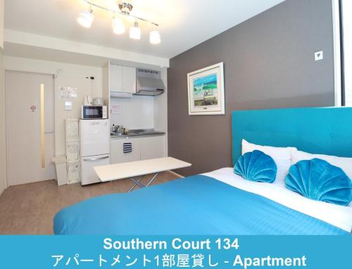 a bedroom with a blue bed and a kitchen at Enoshima Guest House 134 / Vacation STAY 60850 in Fujisawa