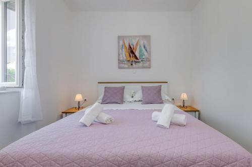 een slaapkamer met een groot roze bed met paarse kussens bij New place in Old town of Trogir, parking in Trogir