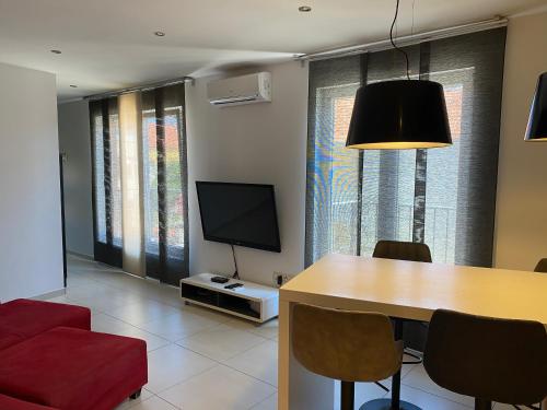 sala de estar con mesa y TV de pantalla plana en Guest House Lorenta, en Vodice