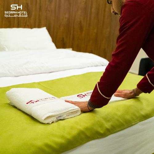 a person is putting towels on a bed at Sedrah Hotel in Irbid