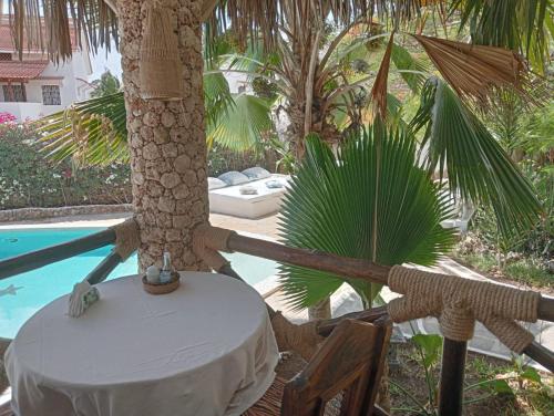 a table and a palm tree next to a pool at Boutique Hotel Nyumbani Tembo in Watamu