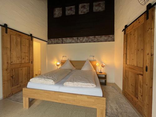 uma cama num quarto com duas portas de madeira em Ferienwohnung Mariandl em Schwangau