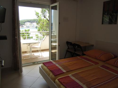 a bedroom with a bed and a view of a balcony at Apartments Roko in Rogoznica