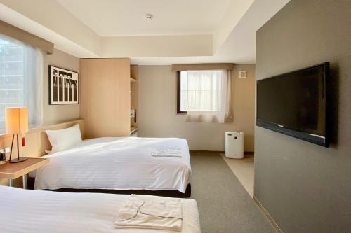 a hotel room with two beds and a flat screen tv at Kyoto Itoya Hotel in Kyoto