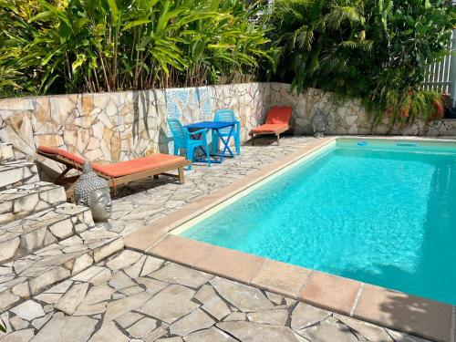 a swimming pool with chairs and a table and a bench at Bungalow avec piscine in Sainte-Marie