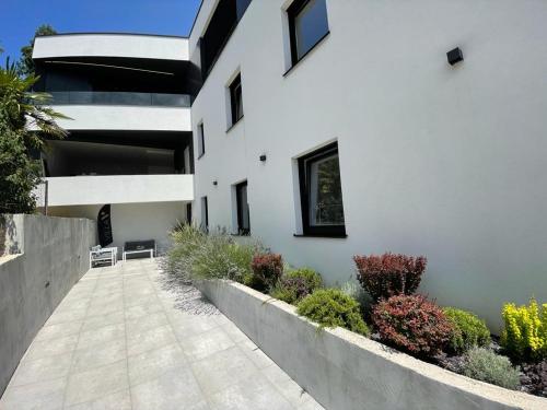 a white building with a walkway in front of it at Aparthotel Villa V with breakfast and free parking in Rijeka