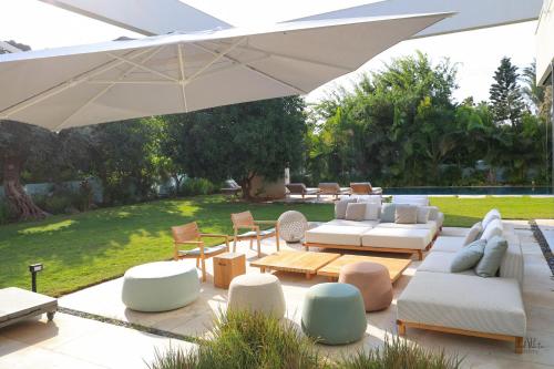 un patio con mobili bianchi e ombrellone di Breathtaking Villa w Pool & Sauna Near the Beach by Sea N' Rent a Herzelia
