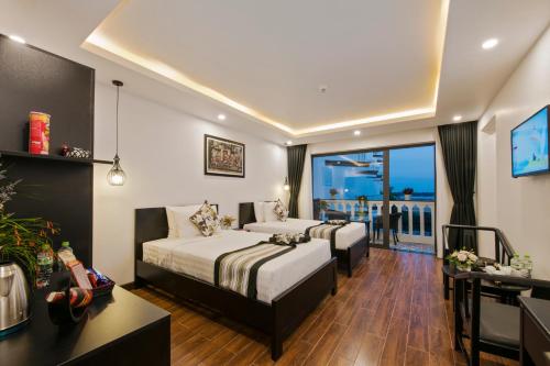 a hotel room with two beds and a balcony at Gem Riverside Hotel Hoi An in Hoi An