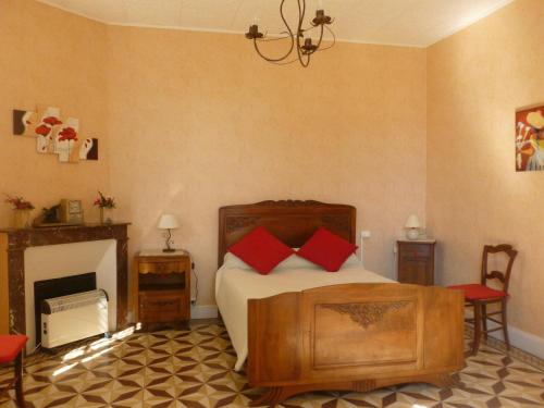 - une chambre avec un lit doté d'oreillers rouges et une cheminée dans l'établissement Gîte les Marronniers, 