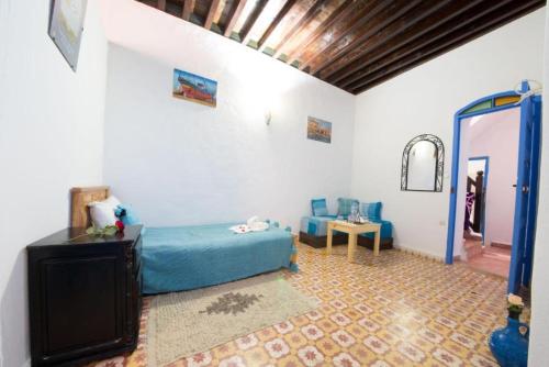 a bedroom with a blue bed and a table at Riad AYLAL in Essaouira