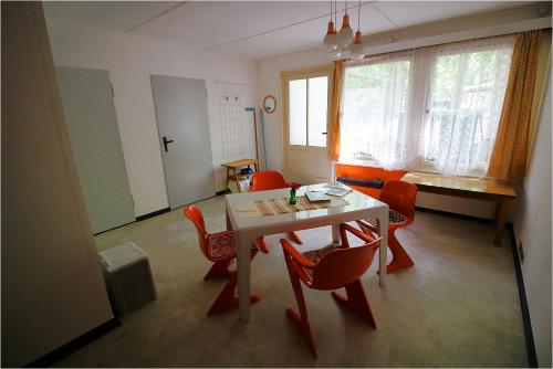 a dining room with a table and red chairs at DDR Bungalow direkt am Strand auf Rügen in Dranske