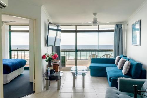 a living room with a blue couch and a view of the ocean at Spectacular Central Surfers Beach Views from Apartment in Gold Coast