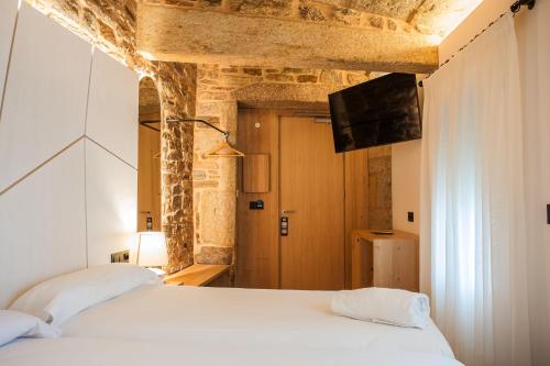 a bedroom with two beds and a flat screen tv at Hotel Plaza Obradoiro by Bossh! Hotels in Santiago de Compostela
