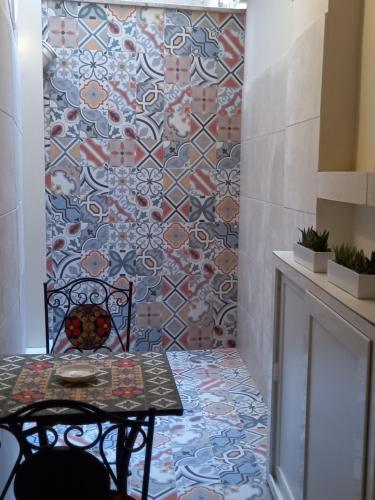 a table and chair in a room with a tile wall at Suite Duomo Trani 6 in Trani