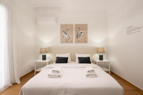 a white bedroom with two beds and two lamps at Vibrant Urban Getaway: Modern 1-Bedroom near Bars, Parks, and Metro in Athens