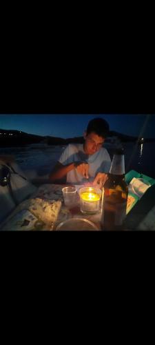 a man sitting at a table with a candle at barca a vela in Portoferraio