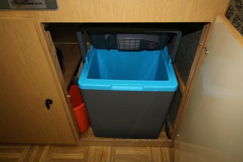 a plastic bin with a blue lid in a cabinet at DDR Kult Wohnwagen direkt am Strand in Kreptitz